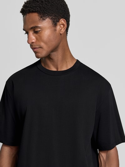 Männermodel trägt Oversized T-Shirt aus reiner Baumwolle von Lindbergh in Schwarz, halbärmelig, glatte Struktur, Nahaufnahme Oberkörper, Herren T-Shirt