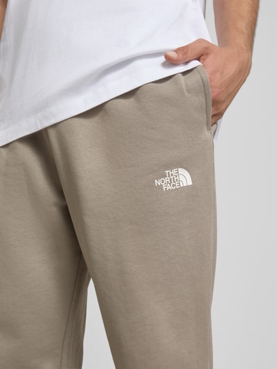 Männermodel trägt Sweatpants mit Logo-Print von The North Face aus Baumwoll-Mix, Slim-Fit, elastischer Bund mit Kordelzug, Nahaufnahme Oberschenkel.