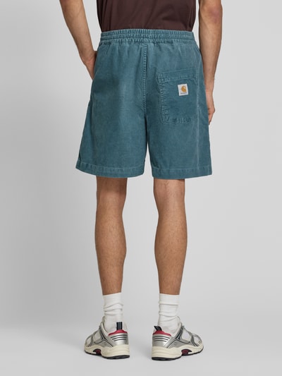 Männermodel trägt korte jeans van puur katoen model 'Reynold' van Carhartt Work In Progress, relaxed fit, elastische band, ganzlichaamsaanzicht achteraan.