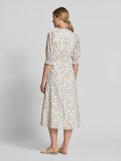 Frauenmodel trägt Midikleid mit floralem Allover-Print Modell 'Valley' von Neo Noir, cremefarben mit blauen Blumen, taillierte Passform, Rückansicht Ganzkörperansicht. Kontext: Damen Midikleid, V-Ausschnitt, Halbarm, Rückenlänge 121 cm, Brustweite 38 cm, Ärmellänge 42 cm.