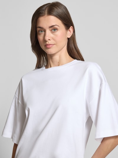 Kobiece modelka nosi Oversized T-Shirt aus reiner Baumwolle von s.Oliver RED LABEL, białe, krótki rękaw, okrągły dekolt, gładki dżersej, logo, półzbliżenie na górną część ciała.