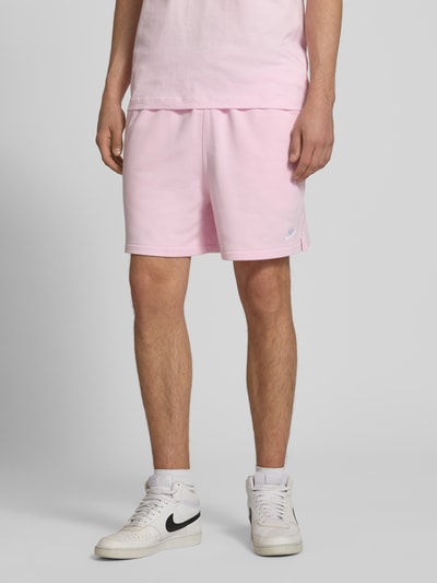 Männermodel trägt Shorts mit Label-Stitching und elastischem Bund von Nike aus Baumwoll-Mix in Rosa, Relaxed-Fit, Nahaufnahme Oberkörper. Kontext: Herren Shorts, Tunnelzug, Bundweite bei Größe M 41 cm, Innenbeinlänge 15 cm.