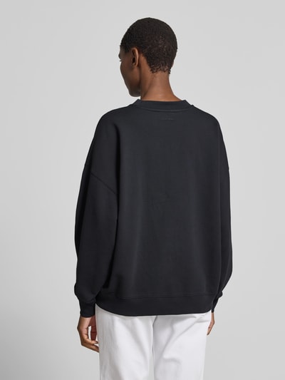 Frauenmodel trägt Oversized Fit Sweatshirt mit Logo-Print von Anine Bing aus Reine Baumwolle, Schwarztöne, elastische Abschlüsse, Rückenlänge bei Größe S 61 cm, Ganzkörperansicht Rückansicht.