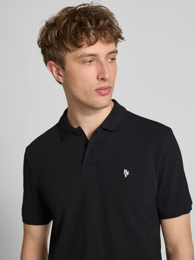 Männermodel trägt Modern Fit Poloshirt mit Logo-Stitching von REVIEW in Schwarz, Baumwoll-Mix, Polokragen, Nahaufnahme Oberkörper. Rückenlänge bei Größe M: 65 cm.