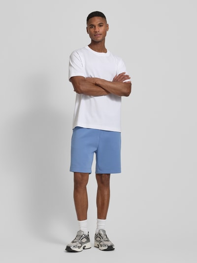 Männermodel trägt Regular Fit Sweatshorts aus Baumwoll-Mix Modell 'JT_GLOBE' von BOSS Green, efekt: jednolity kolor, krój regular fit, z napisem z logo, szwy, ściągacz, tunel, wpuszczane kieszenie, boczna kieszeń zapinana na zamek błyskawiczny, wykończenie materiału: dzianina dresowa, mieszanka bawełny, Ganzkörperansicht von vorne.