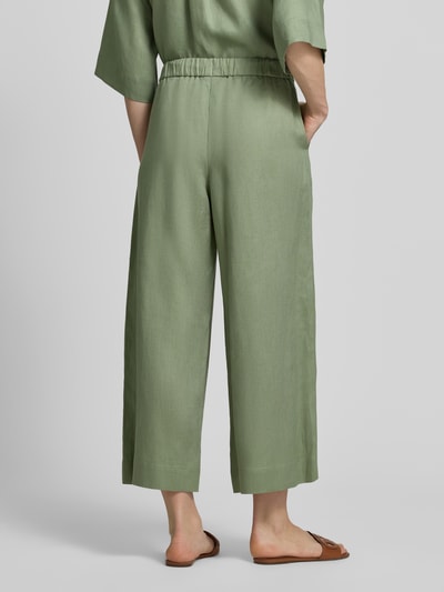 Frauenmodel trägt Culotte aus Leinen mit elastischem Bund Modell 'CANNETI' von MM by Max Mara in hellem Grün, glatte Textur, Wide Leg Fit, französische Eingrifftaschen, Ganzkörperansicht Rückansicht.