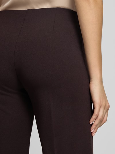 Frauenmodel trägt Flared Fit Stoffhose mit Bügelfalten von Rinascimento in Dunkelbraun, glatte Textur, Detailaufnahme, Material-Mix mit Stretch-Anteil.