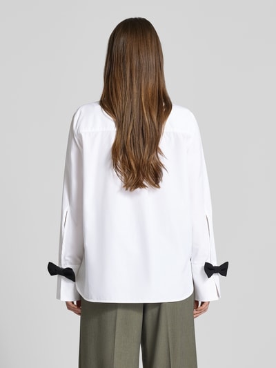 Frauenmodel trägt Hemdbluse mit Knopfleiste von Marella aus reiner Baumwolle, locker geschnitten, weiß, schwarze Schleifen, Ganzkörperansicht Rückansicht.