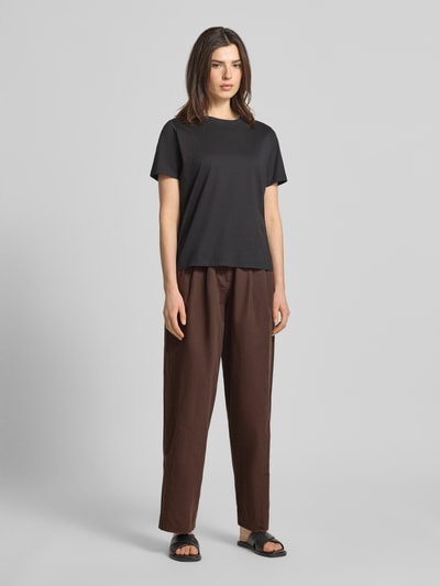 Frauenmodel trägt Wide Leg Hose mit Eingrifftaschen Modell 'QUINN' von Scotch & Soda aus Baumwoll-Leinen-Mix in Braun, Ganzkörperansicht von vorne.