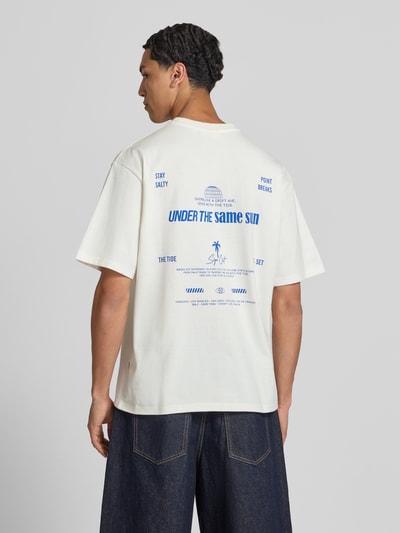 Männermodel trägt T-Shirt mit Statement-Print und Rundhalsausschnitt von Redefined Rebel, Baumwoll-Mix, Relaxed-Fit, Modell 'Bruno', Rückansicht, Rückenlänge 70 cm bei Größe M.