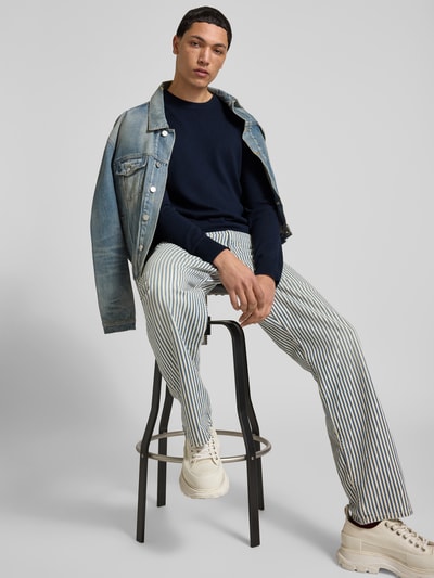 Männermodel trägt Slim Fit Pullover aus Woll-Mix von Filippa K in Dunkelblau, Strick-Optik, Rundhalsausschnitt, Ganzkörperansicht von vorne.