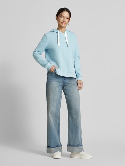 Frauenmodel trägt Regular Fit Hoodie aus Baumwoll-Mix von Tom Tailor Denim in Hellblau mit Stickerei, Kapuze und gerippten Abschlüssen, Ganzkörperansicht von vorne.