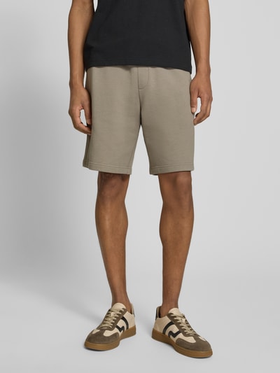 Männermodel trägt Regular Fit Sweatshorts aus reiner Baumwolle Modell 'DAYONO' von HUGO, efekt: jednolity kolor, krój regular fit, nadruk z logo, ściągacz: elastyczny z tunelem, wpuszczane kieszenie, wykończenie materiału: dzianina dresowa, materiał: bawełna. Ganzkörperansicht von vorne.