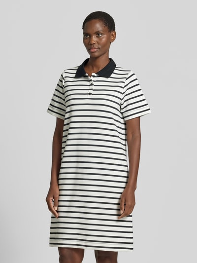 Frauenmodel trägt knielanges Polokleid mit kurzer Knopfleiste Modell 'BARNI' von Soyaconcept im Material-Mix mit Modal-Anteil, Gerader-Schnitt, Polokragen, schwarz-weiß gestreift, Ganzkörperansicht von vorne.