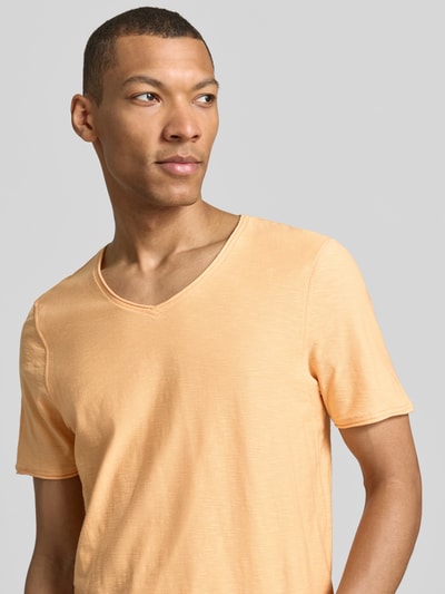 Mannenmodel draagt Regular Fit T-shirt met V-hals van MCNEAL in lichtoranje, puur katoen, rolzoom, ruglengte maat M 70 cm, close-up bovenlichaam