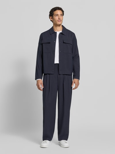 Männermodel trägt Stoffhose mit Bügelfalte Modell 'GRANT' von Casual Friday, dunkle Farbe, straight Fit, Ganzkörperansicht von vorne.