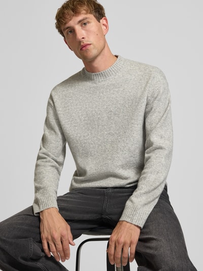 Männermodel trägt Relaxed Fit Strickpullover aus Material-Mix mit Baumwoll-Anteil von REVIEW in Hellgrau, elastische Abschlüsse, Nahaufnahme Oberkörper.