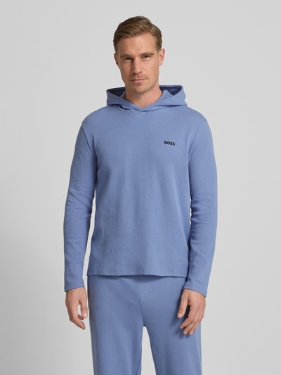 Männermodel trägt Comfort Fit Langarmshirt aus Baumwoll-Mix Modell 'WAFFLE' von BOSS in Hellblau mit Kapuze und Label-Schriftzug, Ganzkörperansicht von vorne.