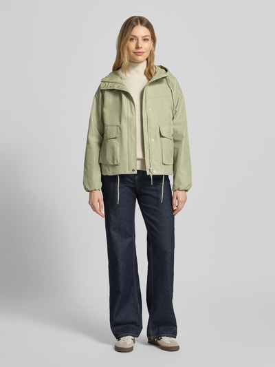 Frauenmodel trägt Regular Fit Parka aus Baumwoll-Mix von s.Oliver RED LABEL in Optik: Unifarben mit Kapuze, Reißverschluss, Langarm, Tunnelzug, Pattentaschen, Farbton Hellgrün, Textur glatte Oberfläche, Ganzkörperansicht von vorne.