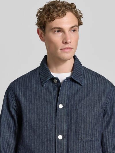 Männermodel trägt Relaxed Fit Jeansjacke aus reiner Bio-Baumwolle Modell 'HERRINGBONE' von Armedangels, denim, wykładany kołnierz, listwa guzikowa, wytłoczone logo, długi rękaw, nakładane kieszenie, bawełna ekologiczna; Nahaufnahme Oberkörper