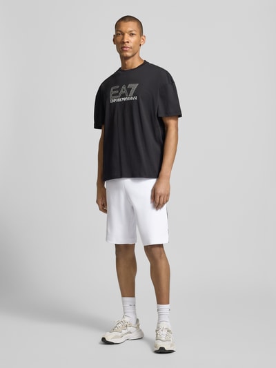 Männermodel trägt Shorts mit elastischem Bund von EA7 Emporio Armani, weiß, Regular Fit, Baumwoll-Mix, Ganzkörperansicht von vorne.