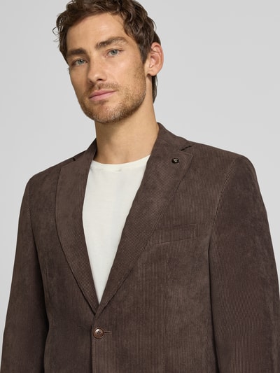 Männermodel trägt Sakko mit Pattentaschen und Reverskragen Modell 'Theo' von Carl Gross in braunem Cord, Nahaufnahme Oberkörper. Regular Fit, Knopfverschluss und Brustleistentasche sind am Sakko sichtbar.
