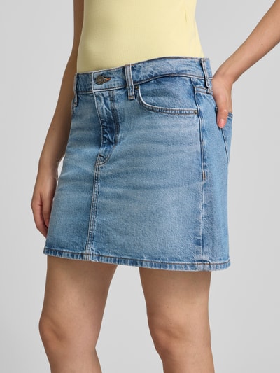 Frauenmodel trägt Jeansrock mit Eingrifftaschen von GUESS, blauer Baumwoll-Elasthan-Mix, gerader Schnitt, Minirock, Nahaufnahme Oberkörper.