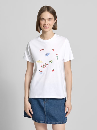 Frauenmodel trägt Damen T-Shirt von Pieces Regular Fit T-Shirt aus reiner Baumwolle Modell 'GAK', Optik: Unifarben, Stickerei, Rundhals, Kurzarm, glatte Baumwollstruktur, weiße Farbe, Detailstickereien vorn, Ganzkörperansicht von vorne.