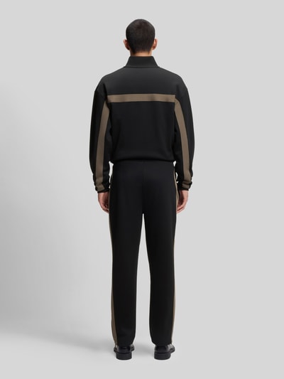 Männermodel trägt Relaxed Fit Jogginghose mit Galonstreifen Modell 'DOLOS' von HUGO, Sweat-Material, unifarben, Ganzkörperansicht Rückansicht.