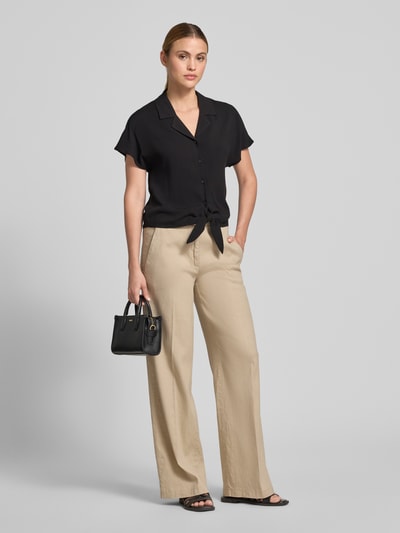 Frauenmodel trägt Regular Fit Bluse aus Viskose mit Knotendetail Modell 'RADIA' von Soyaconcept, Reverskragen, Knopfleiste, schwarze Farbe, glatte Textur, Kontext: Damen Bluse, reine Viskose, Rückenlänge 55 cm, Ärmellänge 10 cm, Ganzkörperansicht von vorne.