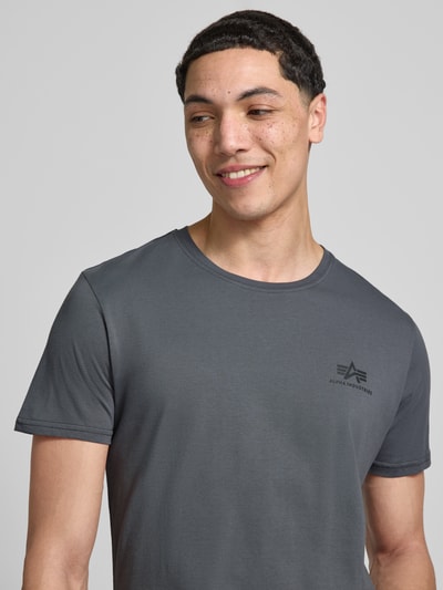 Mannenmodel draagt T-shirt met Label-Details model 'BASIC' van Alpha Industries in grijs, puur katoen, recht model, ronde hals, ruglengte bij maat M 67 cm, Nahaufnahme bovenlichaam.