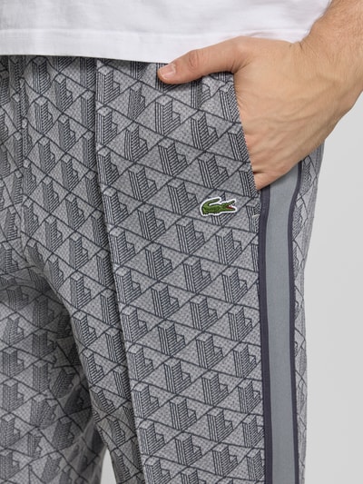 Männermodel trägt Regular Fit Sweathose mit Baumwoll-Anteil von Lacoste, Optik: Allover-Muster, Kontraststreifen, Label Patch, Sweat, seitliche Eingrifftaschen, Nahaufnahme Oberkörper