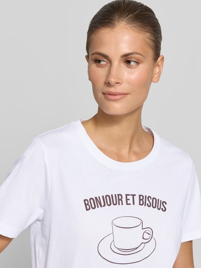 Frauenmodel trägt Damen T-Shirt mit Motiv-Print Modell 'SOBBE' von B.Young aus Reine Baumwolle, Regular-Fit, weiß, Rundhalsausschnitt, Motiv-Print und Schriftzug, Rückenlänge bei Größe S 60 cm, Nahaufnahme Oberkörper.