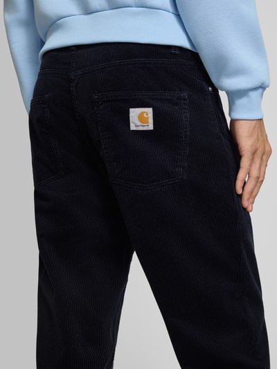 Männermodel trägt Straight Fit Hose aus reiner Baumwolle in Cord-Optik von Carhartt Work In Progress, dunkle Farbe, 5-Pocket-Design, Nahaufnahme Rückansicht.
