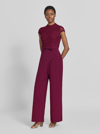Frauenmodel trägt Regular Fit Jumpsuit mit Zierschleife von Adrianna Papell in Dunkelrot mit floraler Spitze, Material-Mix, Ganzkörperansicht von vorne.