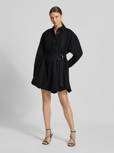 Frauenmodel trägt tailliertes, schwarzes Hemdblusenkleid aus reiner Baumwolle Modell 'KUMIRA' von HUGO, Mini-Länge, Ganzkörperansicht von vorne.