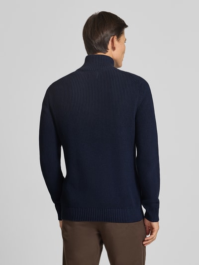 Männermodel trägt Slim Fit Strickpullover aus reiner Baumwolle mit Troyer-Kragen von MCNEAL, dunkelblau, gerippte Abschlüsse, Ganzkörperansicht Rückansicht. Rückenlänge ca. 72 cm, Ärmellänge ca. 74 cm, langärmliges Design, KI-modifiziertes Bild.