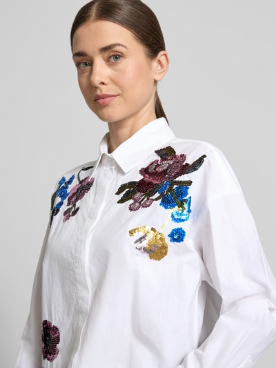 Kobiece modelka nosi Boxy Fit Bluse mit Pailletten od Oui, biała bawełna, naszyte cekiny, kołnierzyk koszulowy, ukryte zapięcie, długość tyłu 55 cm, długość rękawa 52 cm, zbliżenie na górną część ciała