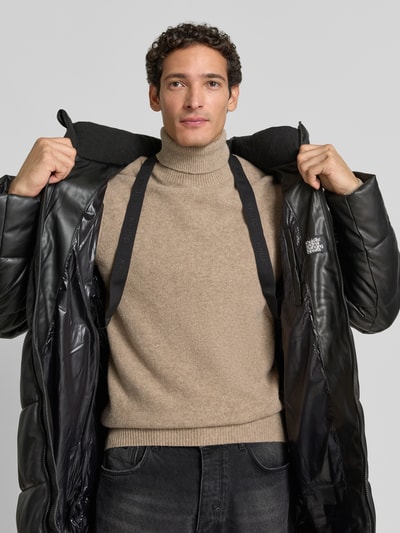 Männermodel trägt Regular Fit Mantel in Stepp-Optik Modell 'EMMET' von khujo in Schwarz, glatte Textur, Nahaufnahme Oberkörper.