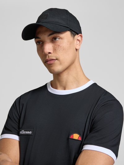 Männermodel trägt Herren T-Shirt mit Logo- und Label-Patch Modell 'RINGETTO' von Ellesse in Schwarz mit weißem Rundhalsausschnitt, Reine Baumwolle, Gerader-Schnitt, Nahaufnahme Oberkörper.