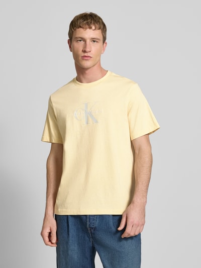 Männermodel trägt T-Shirt mit Label-Print und Rundhalsausschnitt von Calvin Klein Jeans in Gelb, Reine Baumwolle, Regular-Fit, Ganzkörperansicht von vorne.