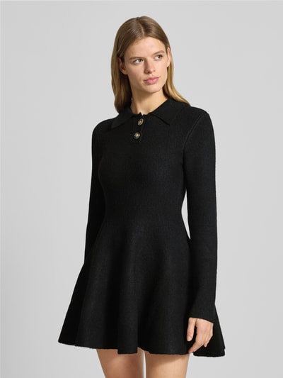 Frauenmodel trägt Cocktailkleid mit kurzer Knopfleiste Modell 'LEXTER' von Bardot im schwarzen Material-Mix mit Hemdblusenkragen, taillierter Schnitt, Ganzkörperansicht von vorne.