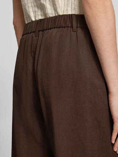 Frauenmodel trägt Wide Fit Leinenhose mit elastischem Bund von comma in Braun mit Drapierungen, reines Leinen, Nahaufnahme Hüfte.