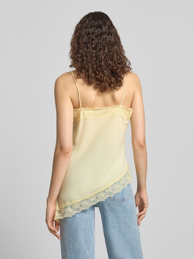 Frauenmodel trägt Top aus Satin mit Spitzenbesatz von REVIEW in Gelb, Asymmetrische Form, V-Ausschnitt, Spaghettiträger, Rückenlänge 54 cm, Ganzkörperansicht Rückansicht.