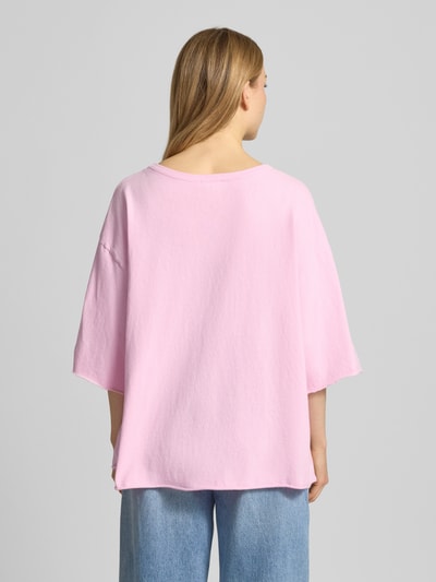Frauenmodel trägt Oversized T-Shirt mit Label-Print Modell 'YKOBOW' von American Vintage aus Reine Baumwolle in Rosa, Ganzkörperansicht Rückansicht.