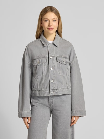 Frauenmodel trägt Oversized Jeansjacke aus Lyocell-Baumwoll-Mix Modell 'PAASITHE' von Armedangels in grauer Denim-Optik, einreihige Knopfleiste, seitliche Eingrifftaschen, langarm, Umlegekragen, Ganzkörperansicht von vorne.