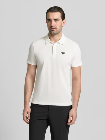 Männermodel trägt Slim Fit Polo-Shirt mit Logo-Applikation von Antony Morato, weiße Baumwolle, Polo-Kragen, Ganzkörperansicht von vorne.