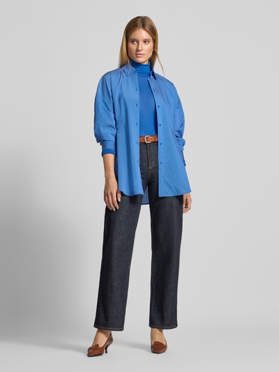 Vrouwenmodel draagt shirt met lange mouwen van Style Icon Collection, puur katoen, nauwsluitend model, semi-transparante look, col, ruglengte bij maat S 59 cm, donkergroene jeans, blauwe overhemd, bruine riem, bruine schoenen, effen lichte achtergrond, volledige lichaamsaanzicht van voren.