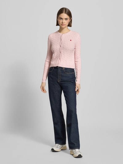 Frauenmodel trägt Shaped Fit Cardigan aus Viskose-Mix Modell 'KATIA' von Only in Optik: Unifarben, Strickoptik, Zopfmuster, einreihige Knopfleiste, Rundhals, Langarm, gerippte Abschlüsse, Materialverarbeitung: Strick, Ganzkörperansicht von vorne.