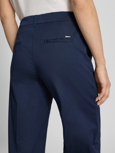 Kobiece modelka nosi chinosy z kantami Chino mit Bügelfalten od Brax, mieszanka bawełny i lyocellu, krój regular fit, ozdobne kieszenie, szerokość w rozmiarze 36: 38 cm, długość wewnętrzna nogawki 80 cm, widok z tyłu zbliżenie na biodra